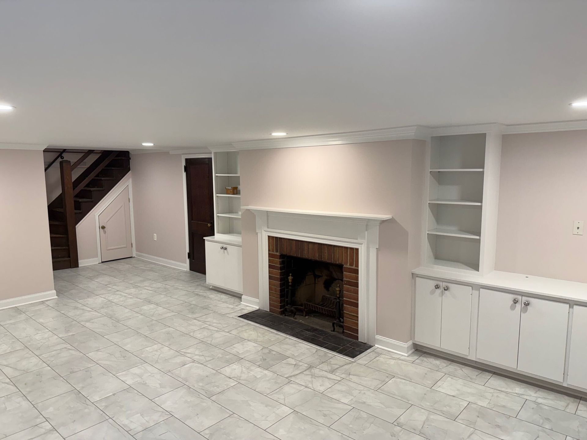 Basement with fireplace, built-in shelves, and stairs.