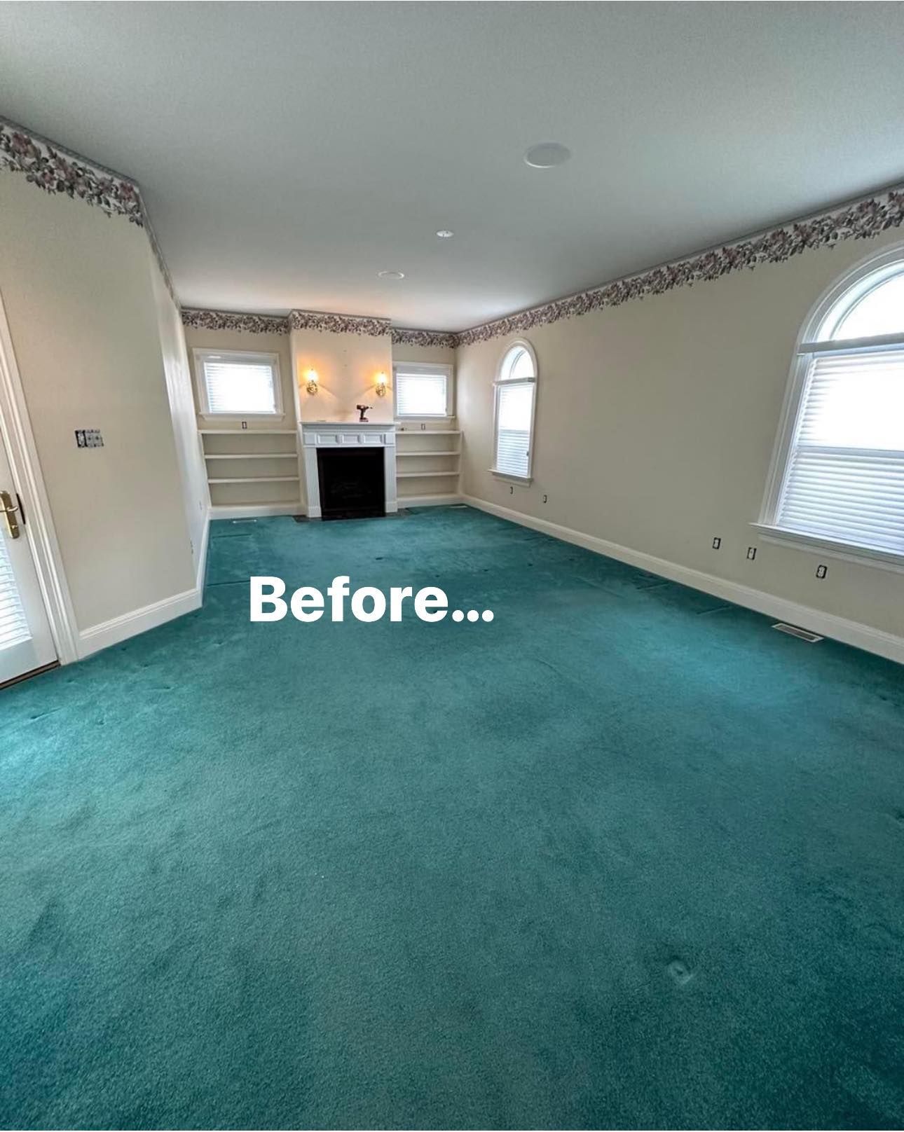 A living room with a green carpet and a fireplace.