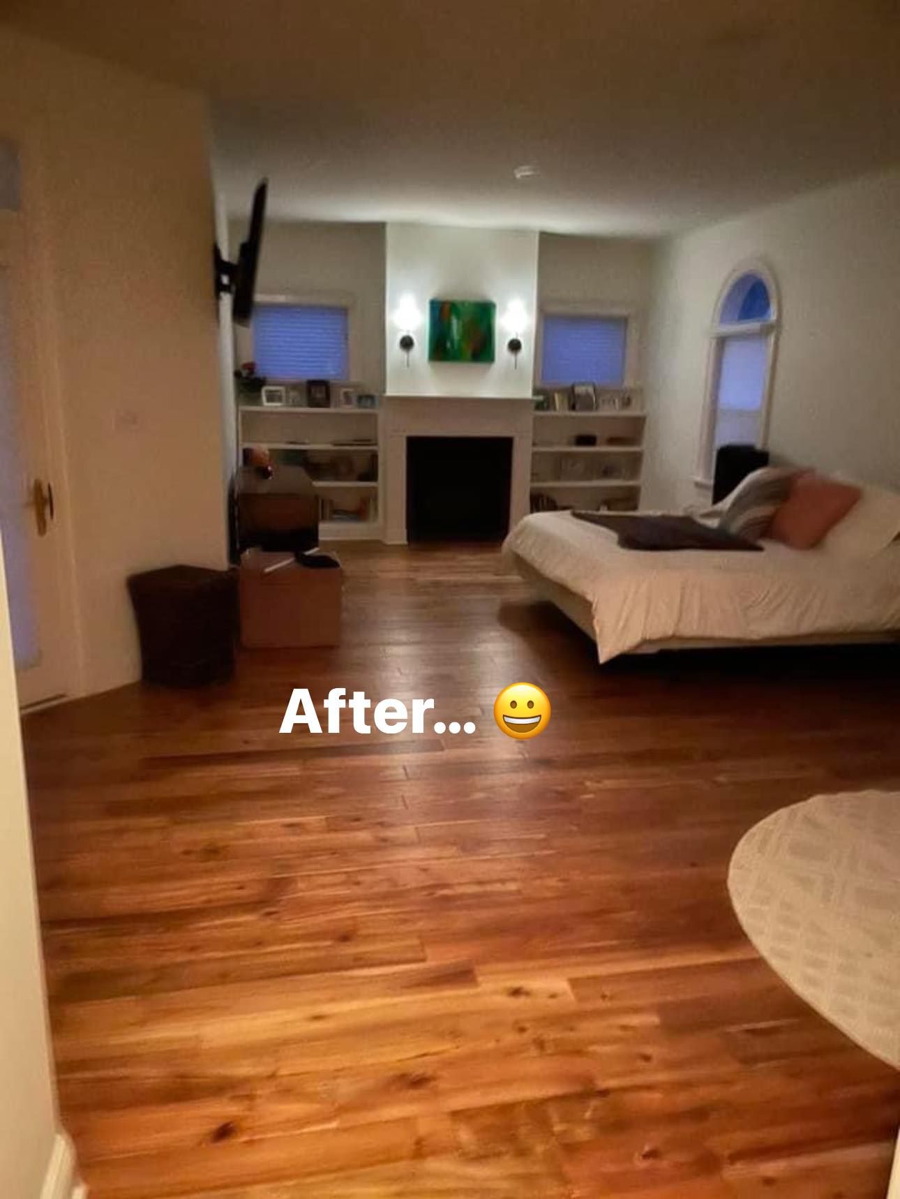 A bedroom with hardwood floors and a bed and a fireplace.