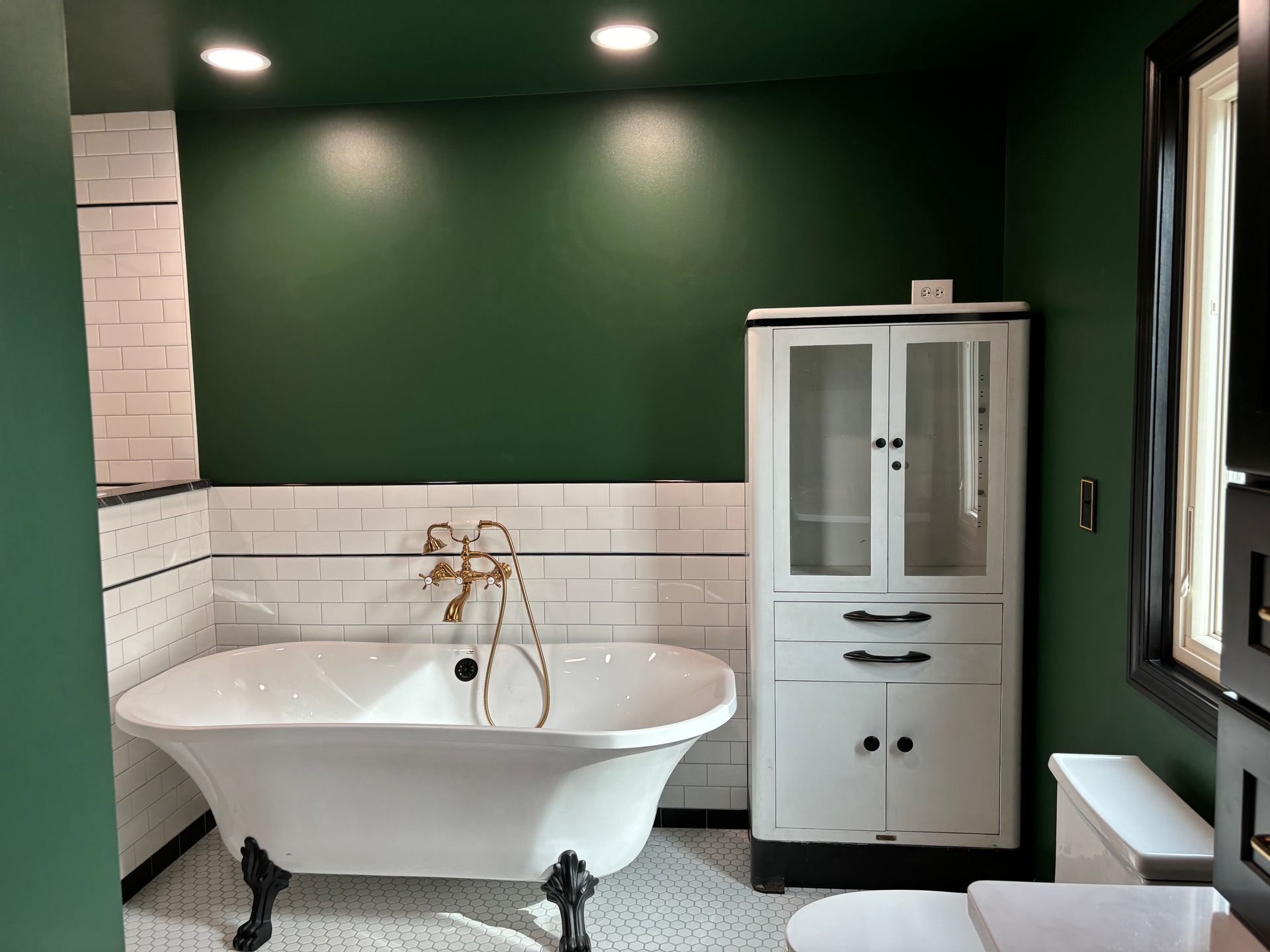 A bathroom with a bathtub , toilet , sink and cabinet.