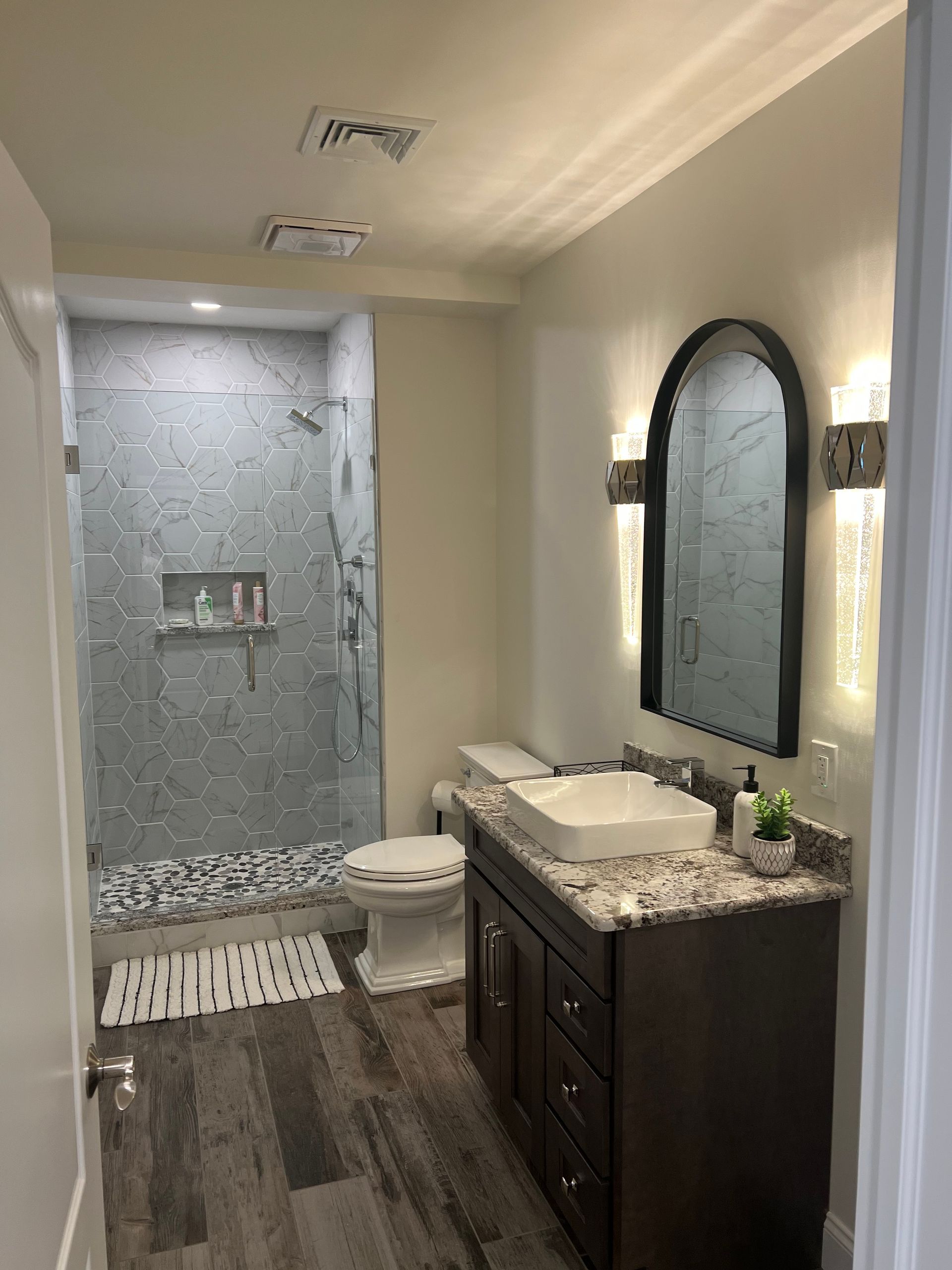 A bathroom with a sink , toilet , shower and mirror.