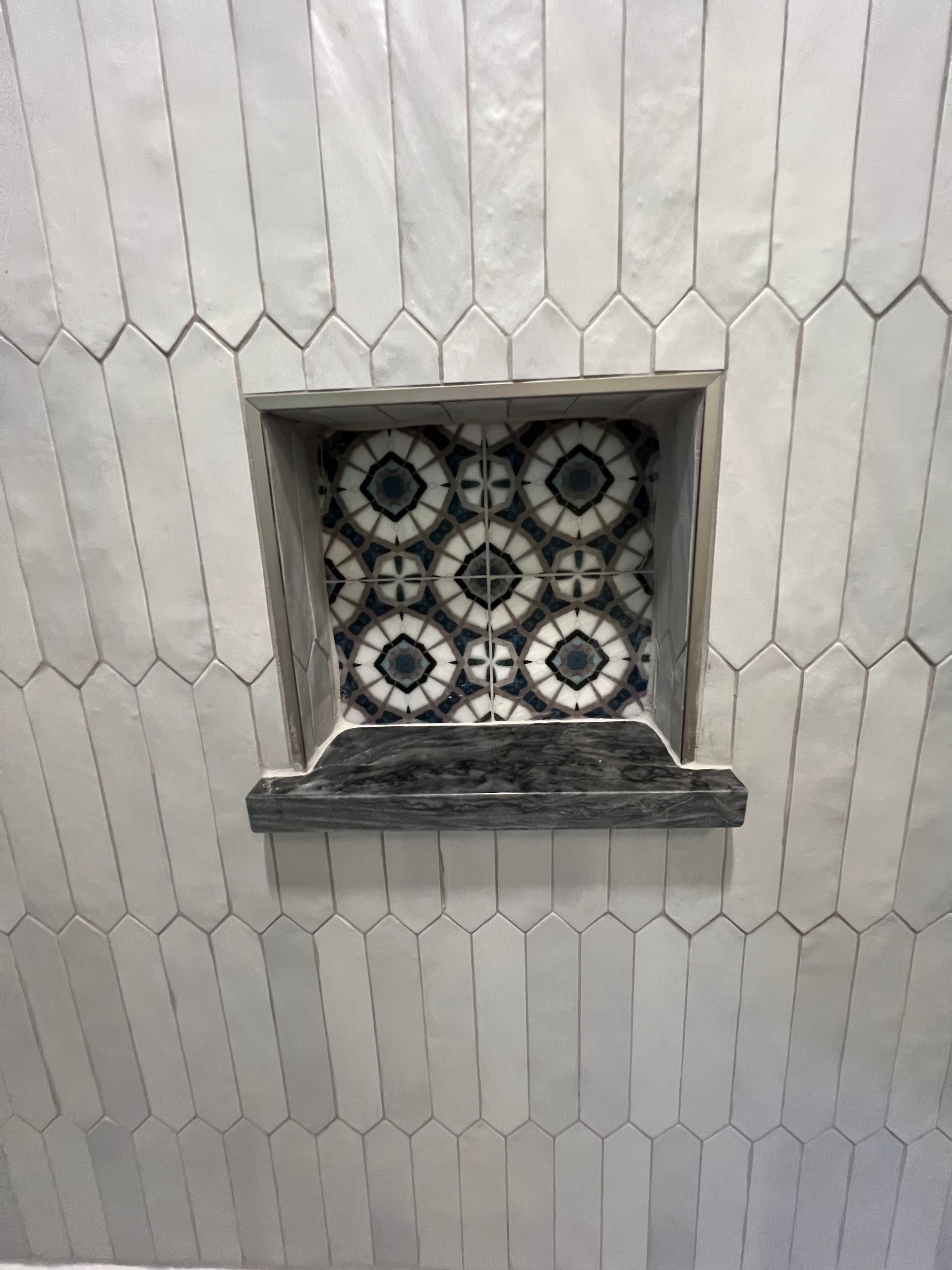 A shower niche in a bathroom with a black and white tile design.