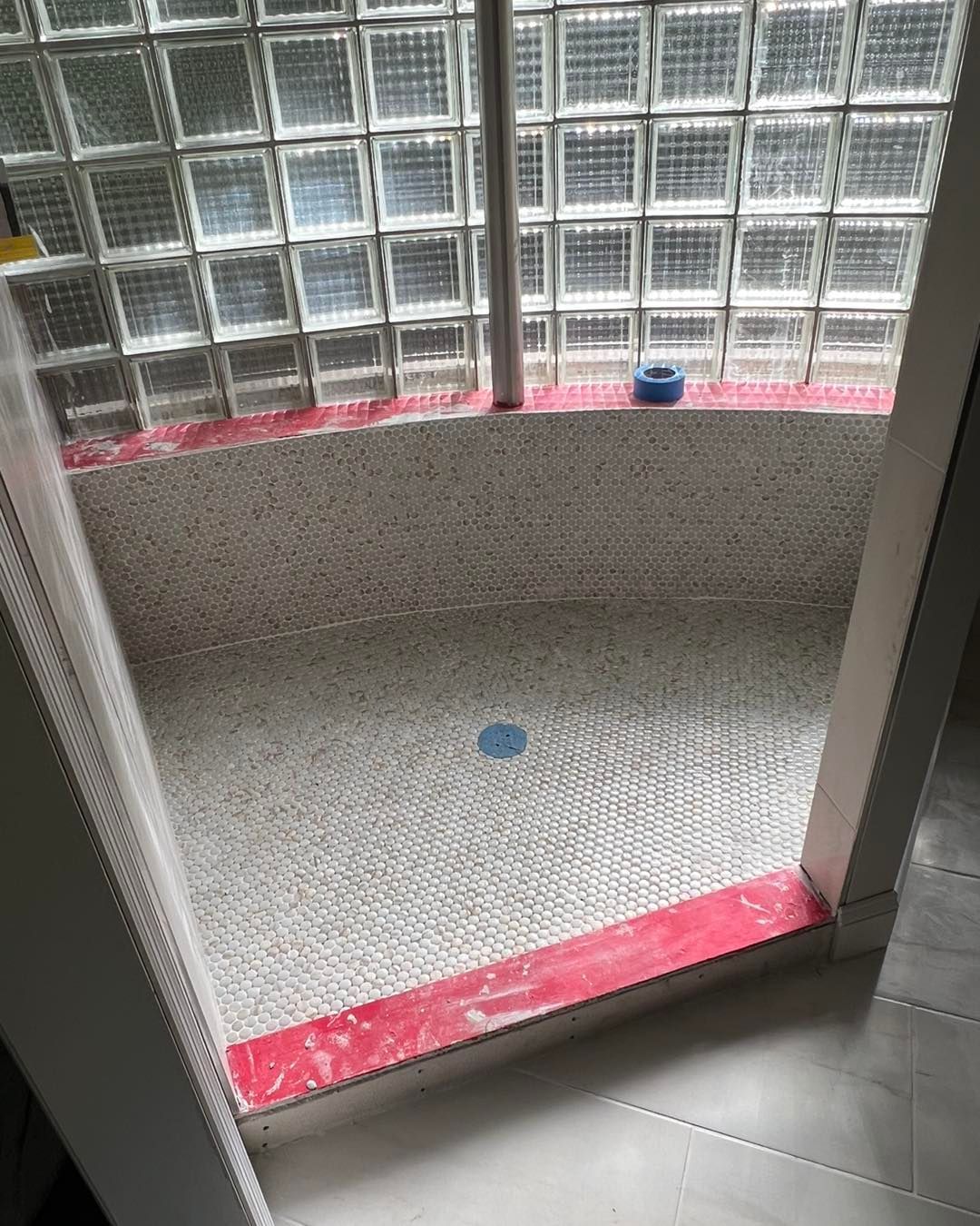 A bathroom with a walk in shower and a glass block window.
