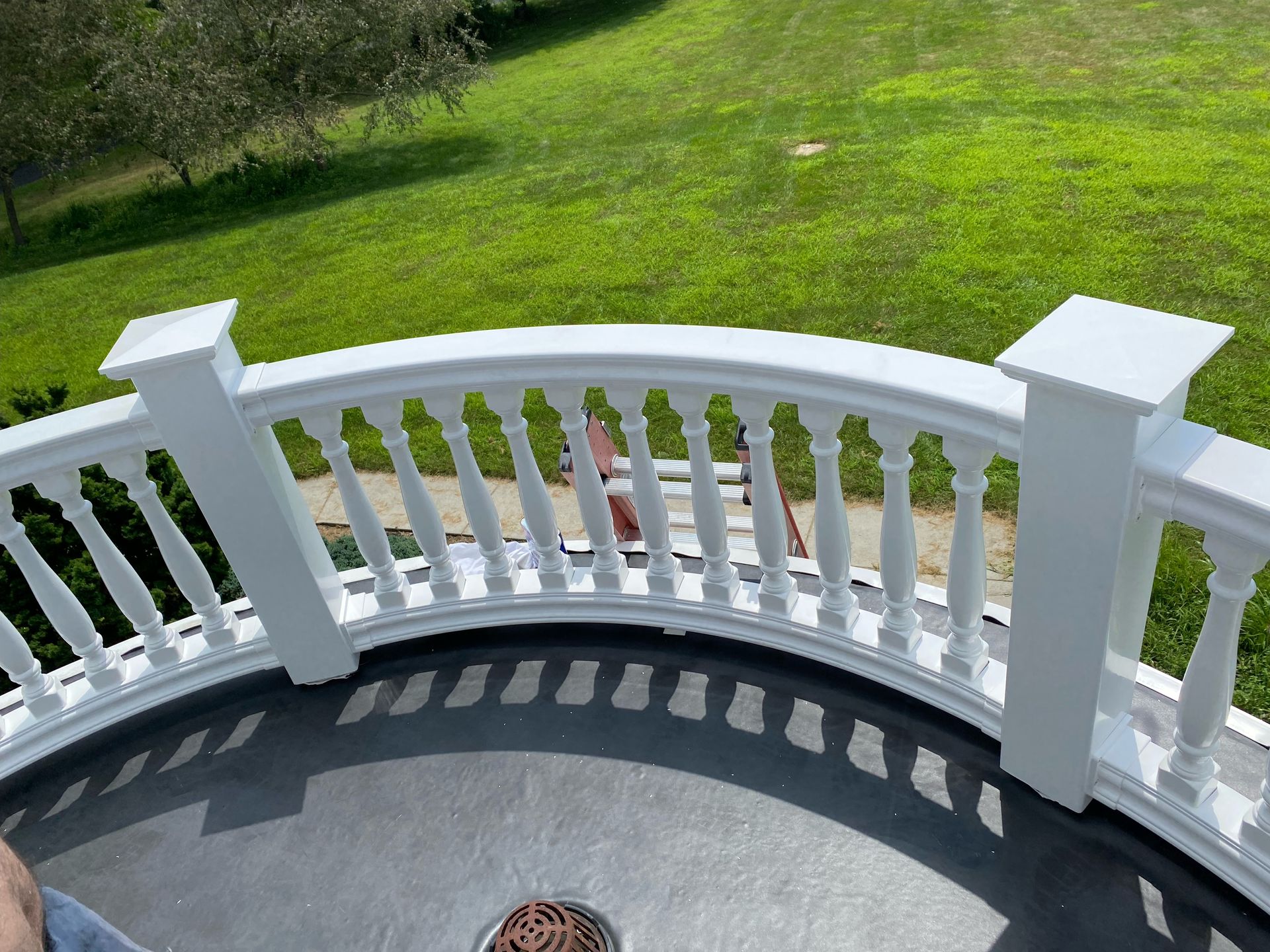 White curved balcony overlooking green lawn.
