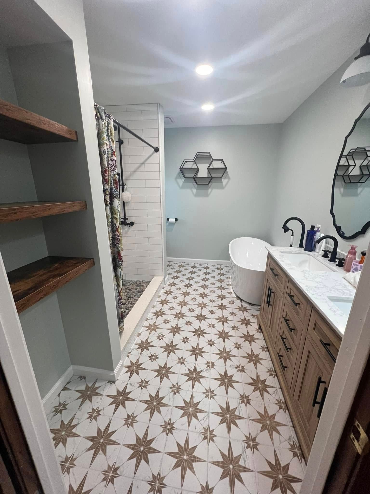 A bathroom with a tub , sink , mirror and shelves.