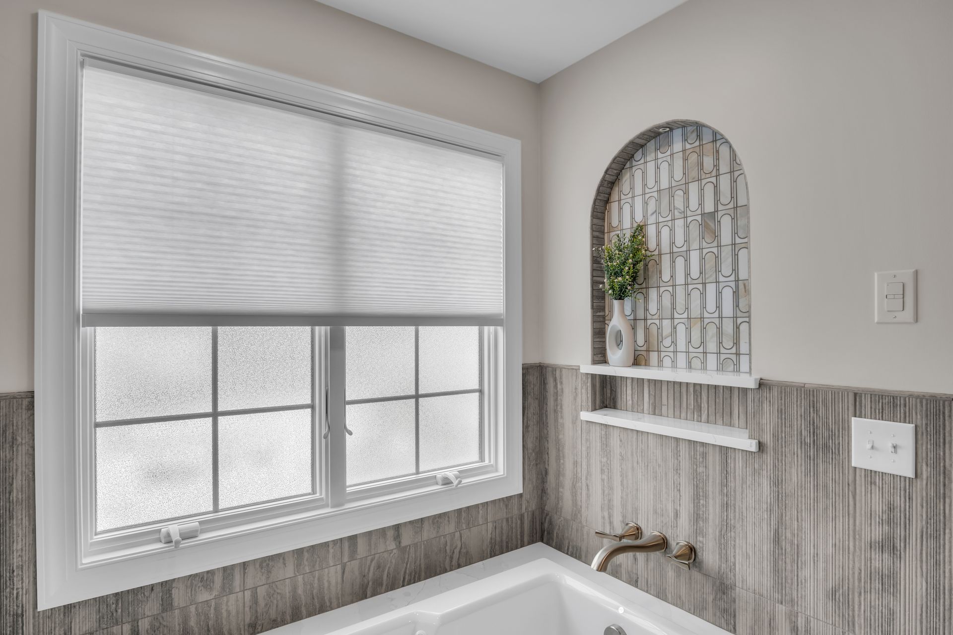 A bathroom with a tub , window , and shelf.