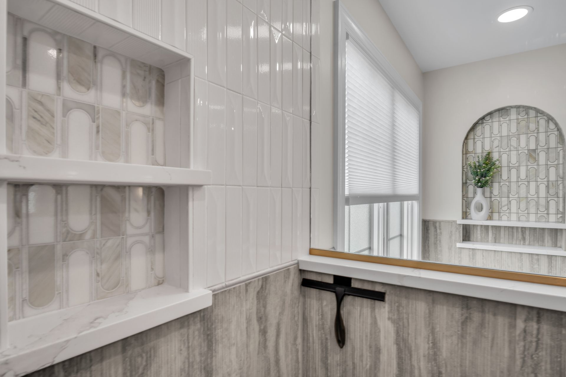 A bathroom with a mirror , shelves , and a window.
