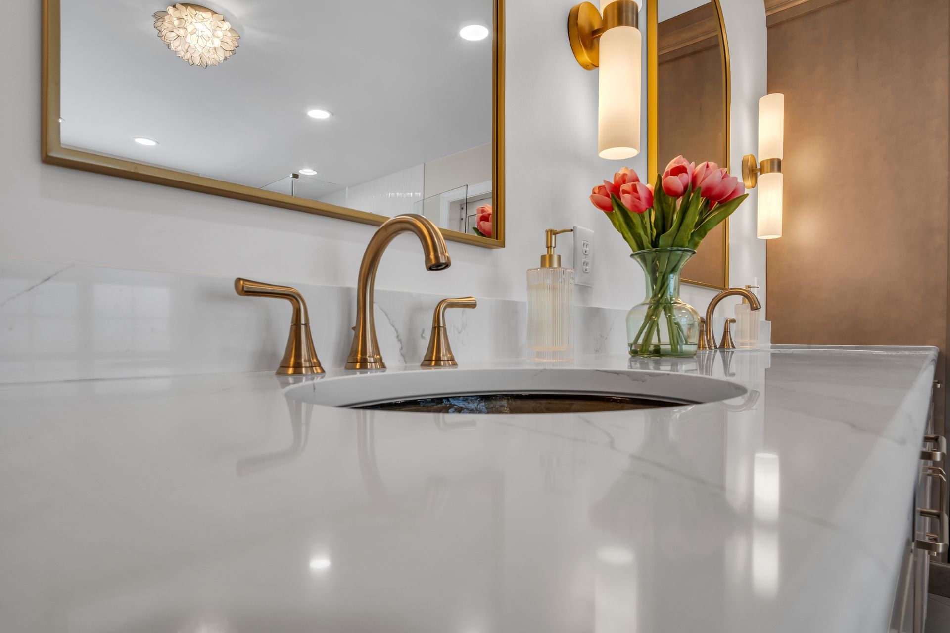 A bathroom sink with a vase of flowers on the counter.