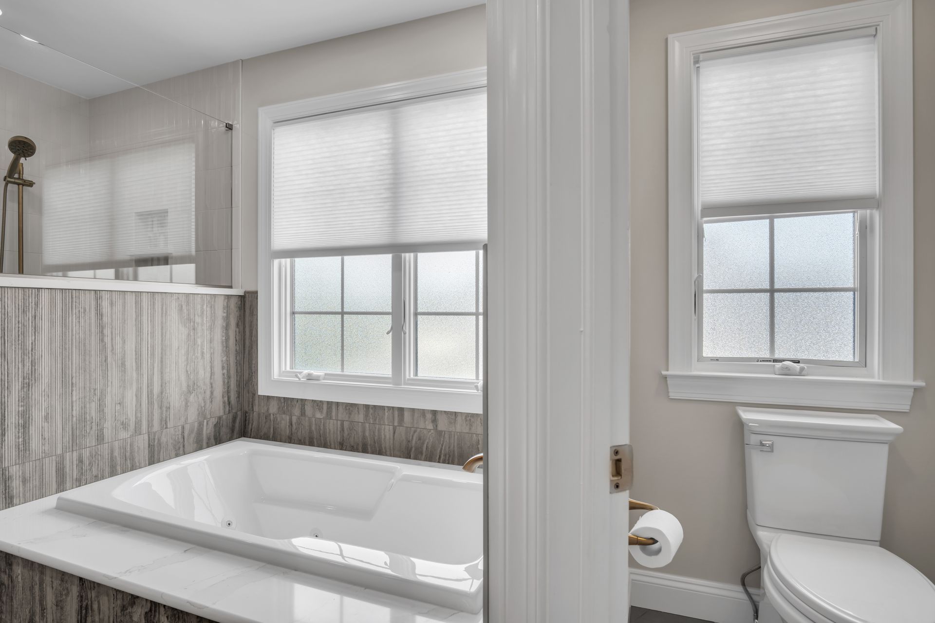 A bathroom with a tub , toilet , and window.
