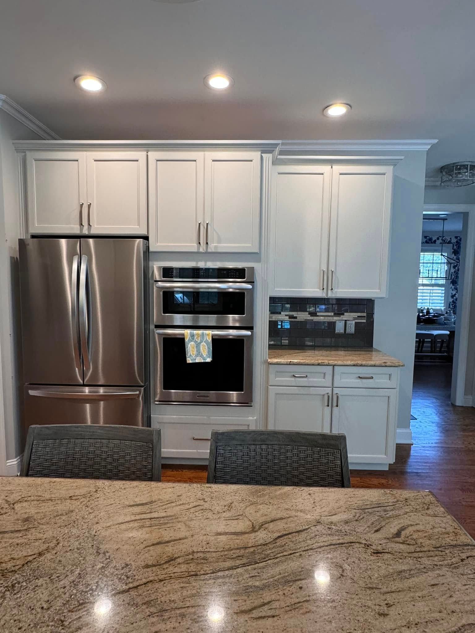 A kitchen with white cabinets , stainless steel appliances , and granite counter tops.