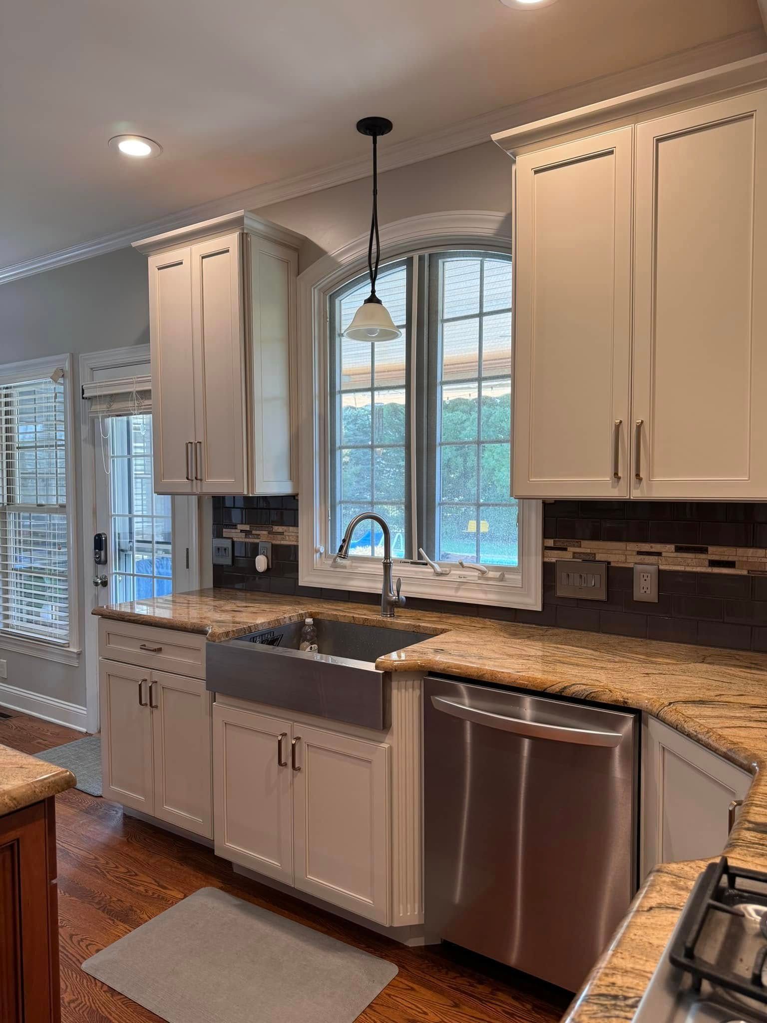 A kitchen with stainless steel appliances , granite counter tops , white cabinets and a sink.