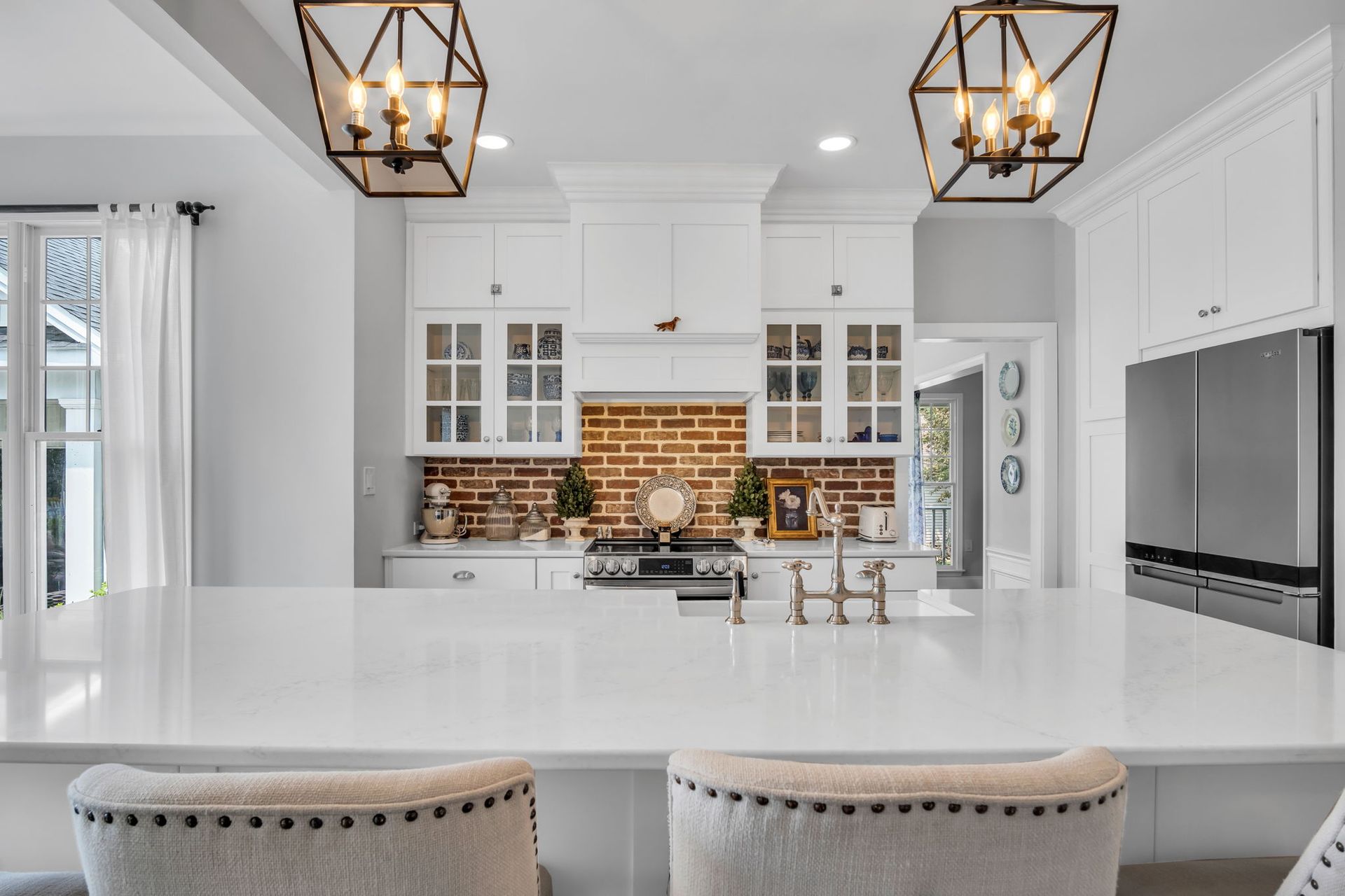 A kitchen with white cabinets and a brick wall.