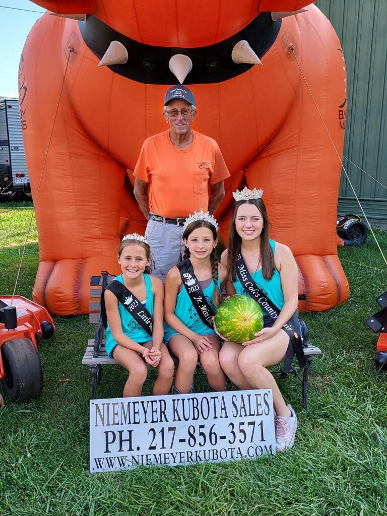 A man and three girls are posing for a picture in front of an inflatable bulldog.