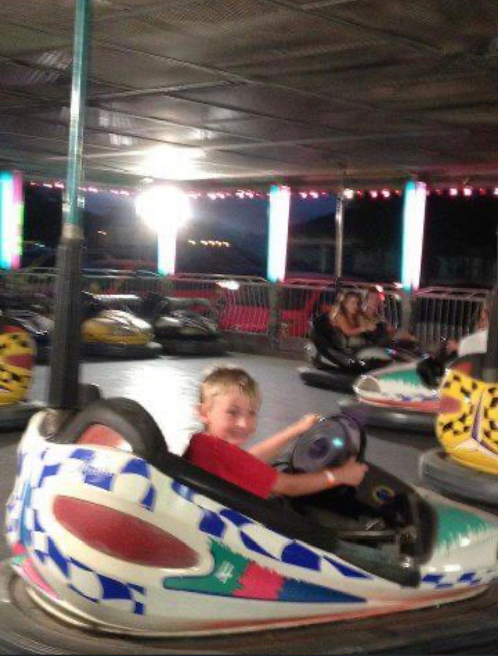 A young boy is riding a bumper car at an amusement park