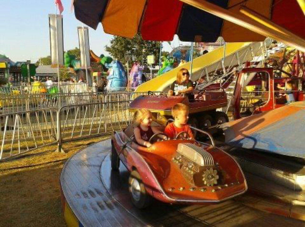 A boy and a girl are riding a car at an amusement park