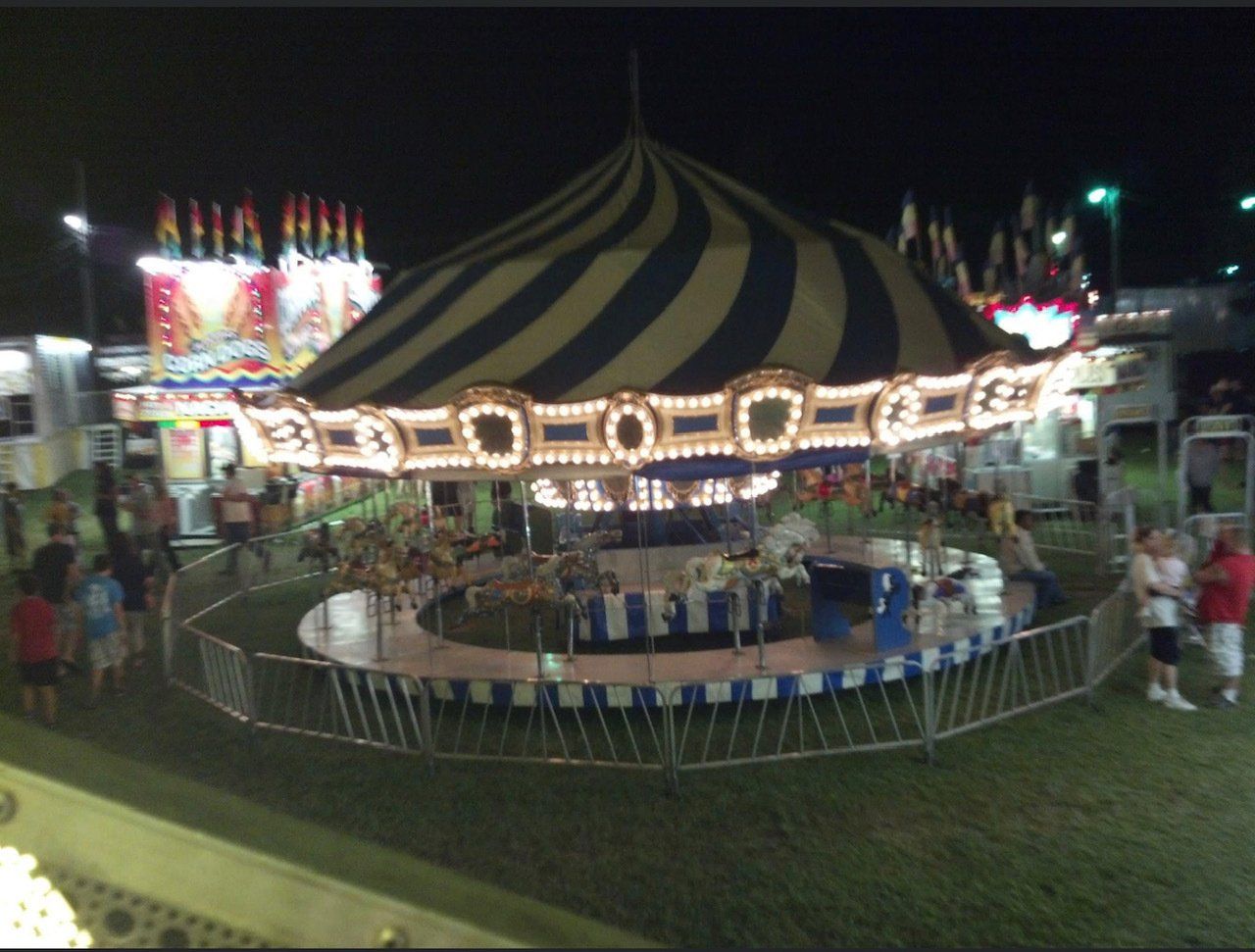 A merry go round at a carnival is lit up at night