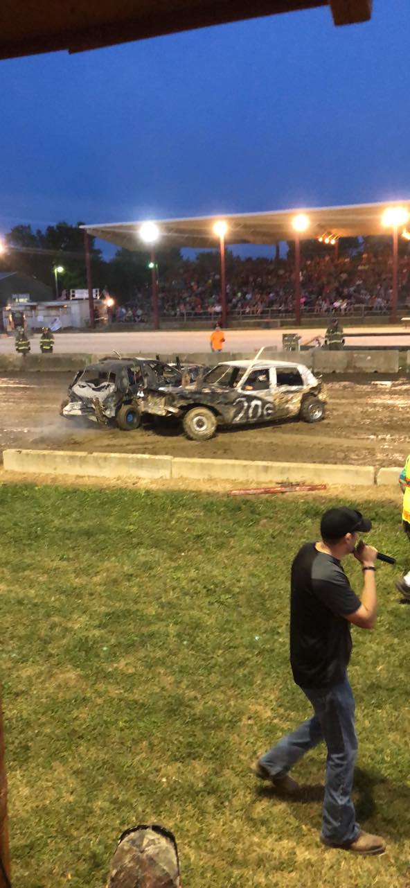 A man is taking a picture of a race car on a dirt track.