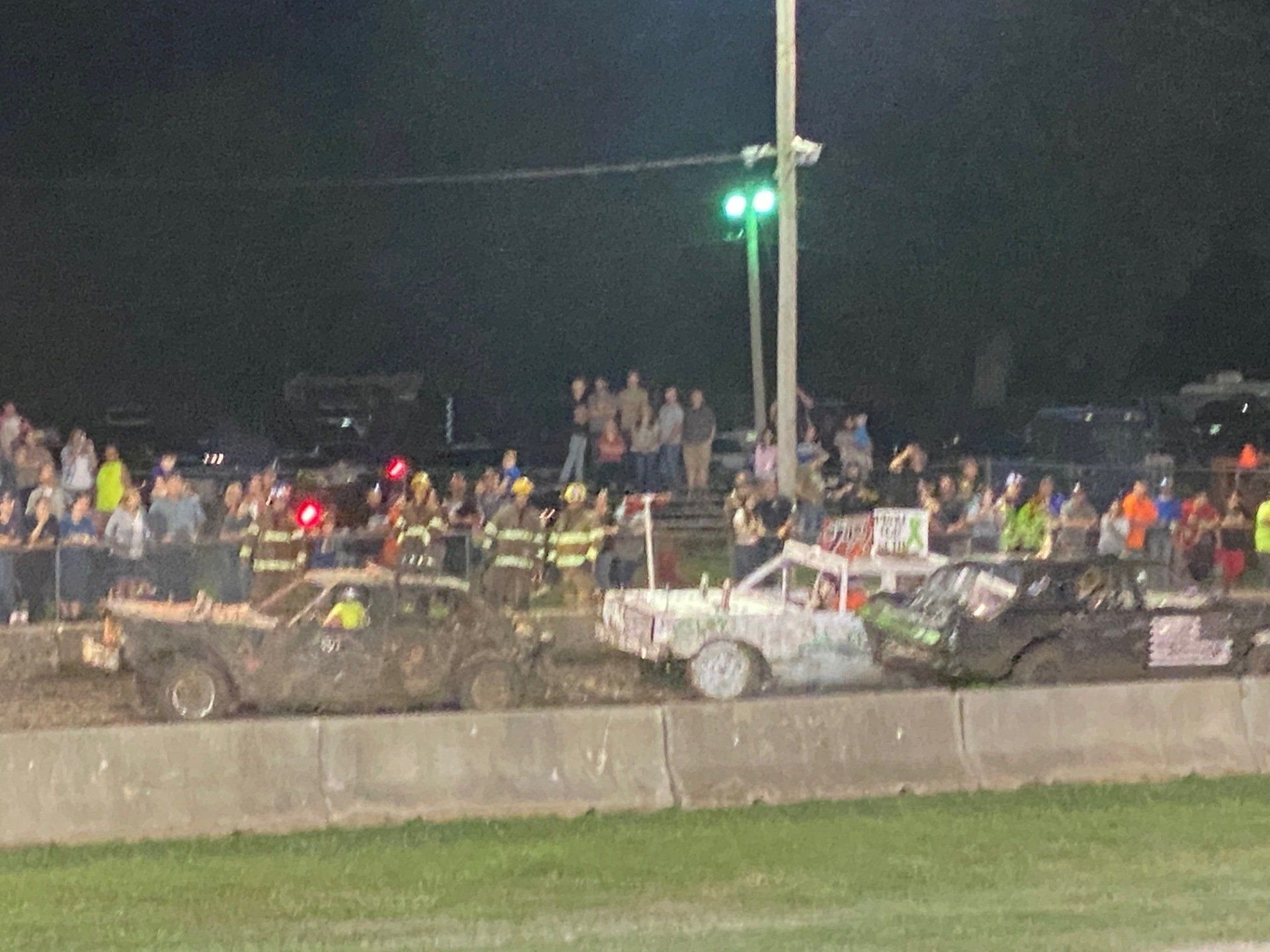 A group of cars are racing on a track at night.