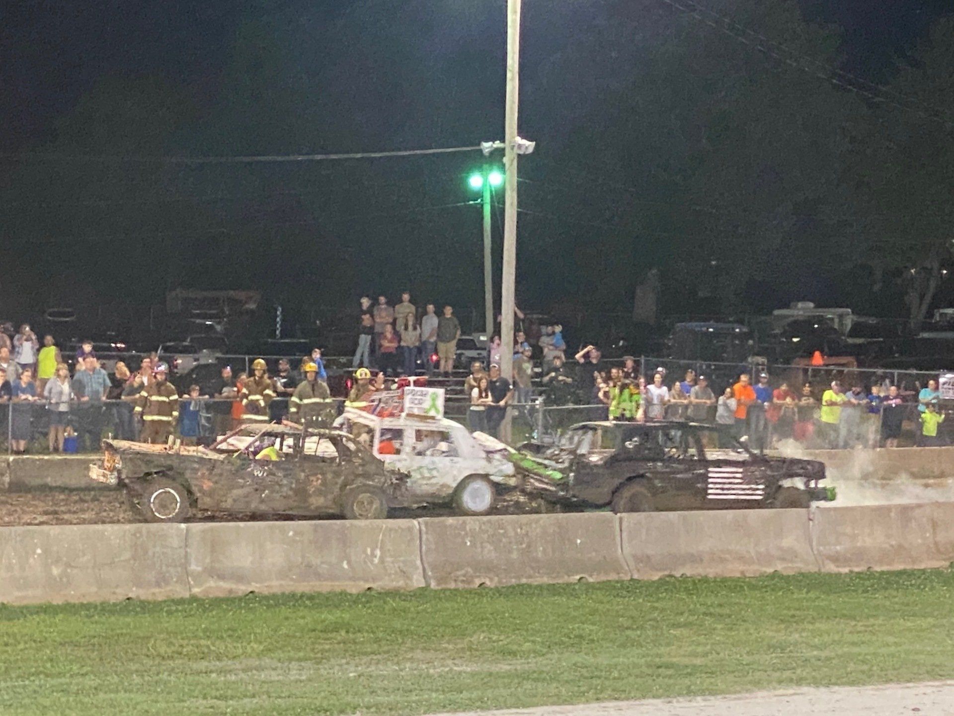 A group of cars are racing on a track at night.
