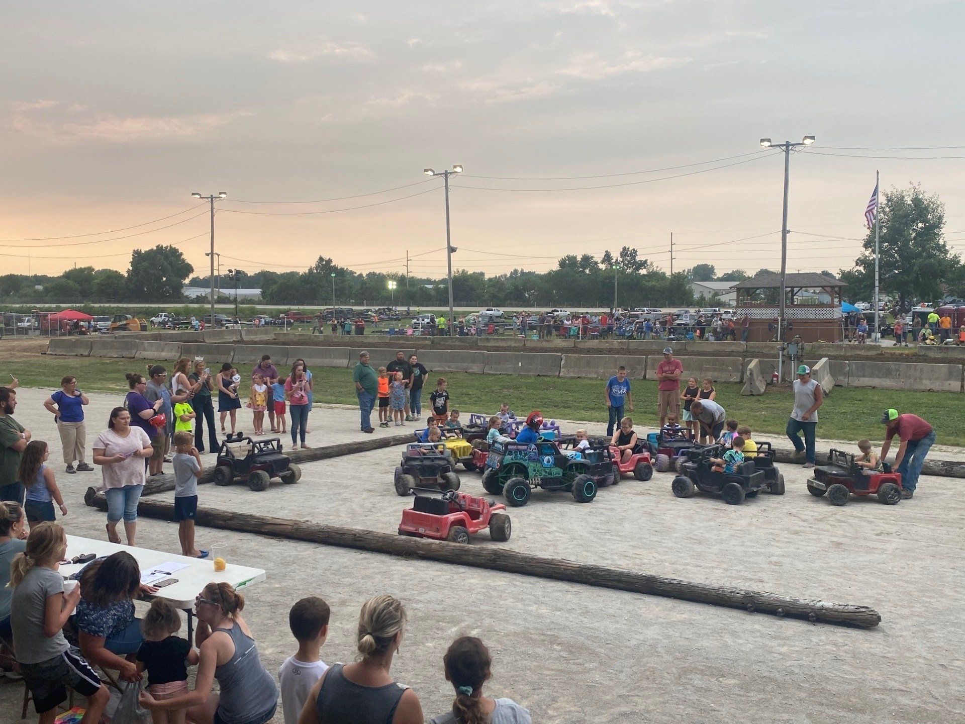 A group of people are watching a race on a dirt track.
