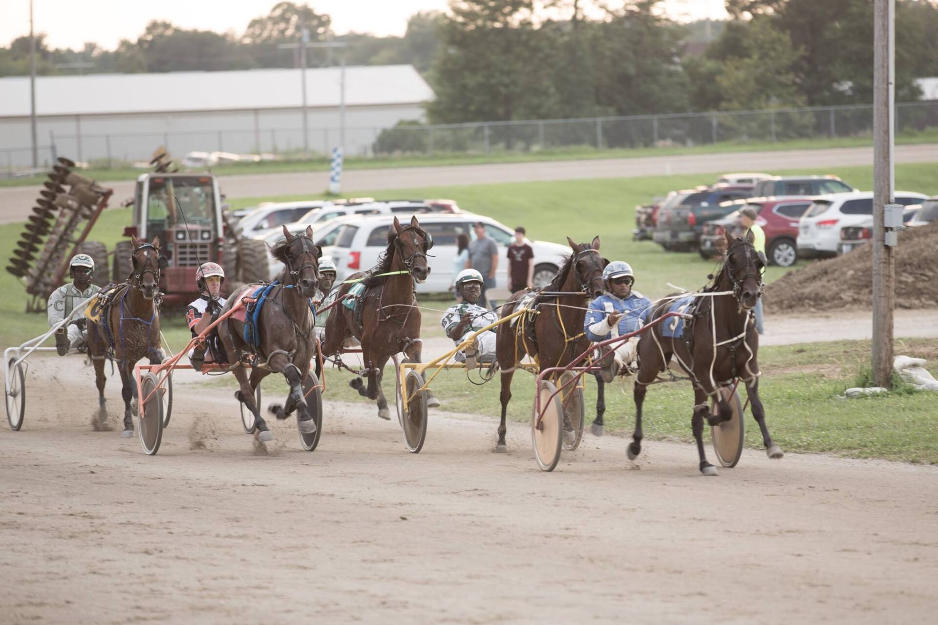 A group of horses are racing on a dirt track.