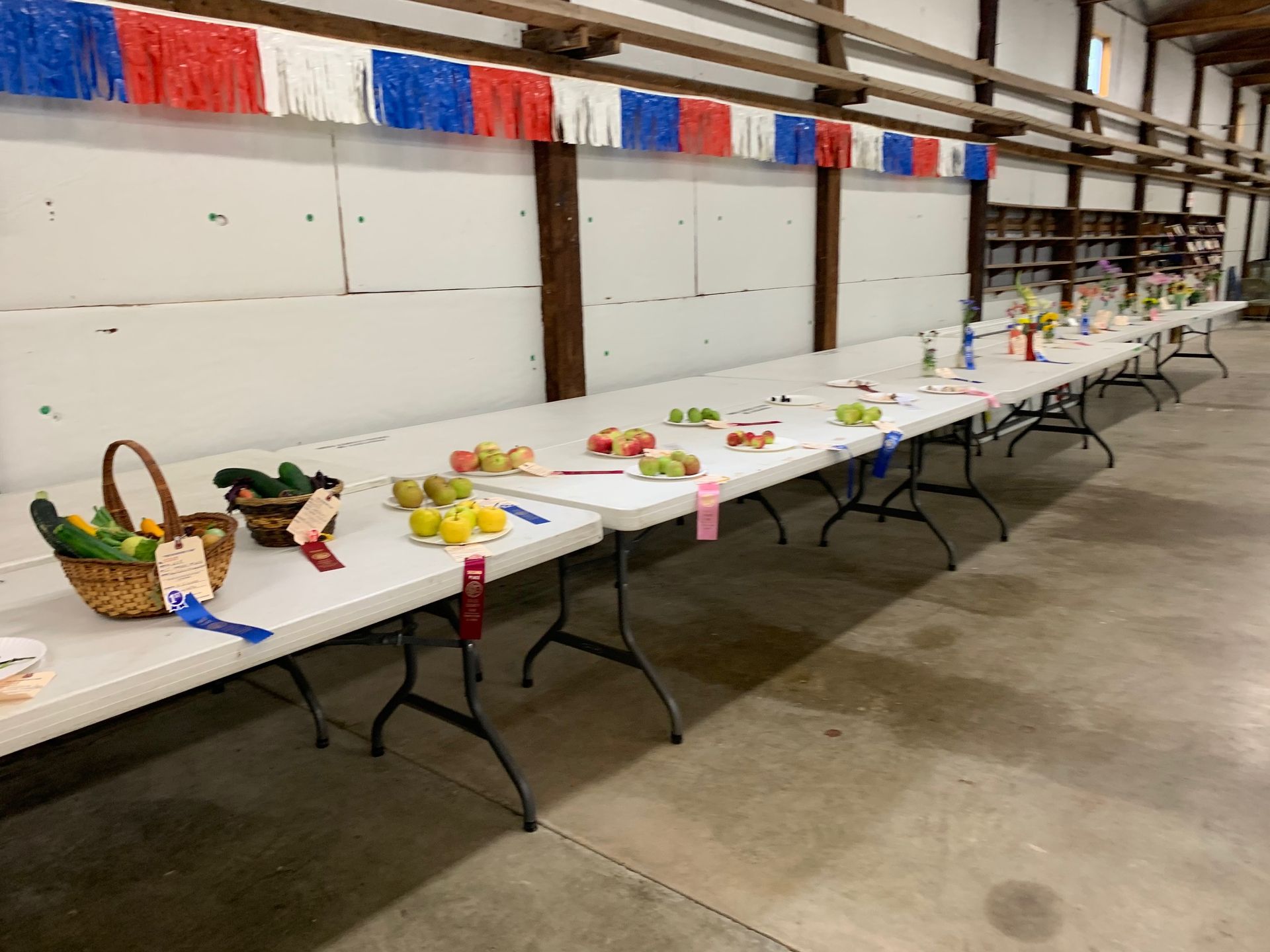 A row of tables with fruits and vegetables on them in a room.