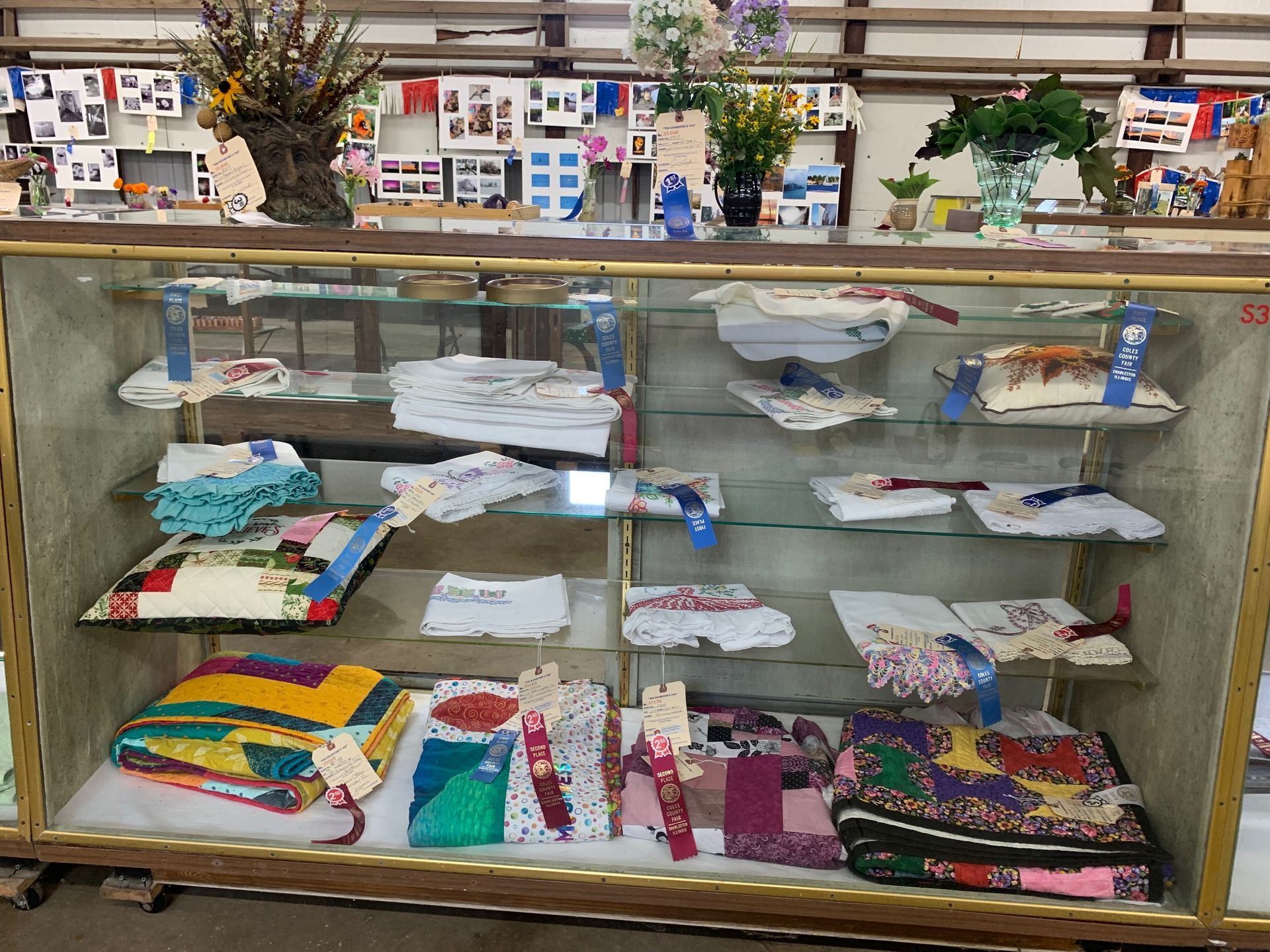 A glass display case filled with quilts and ribbons.