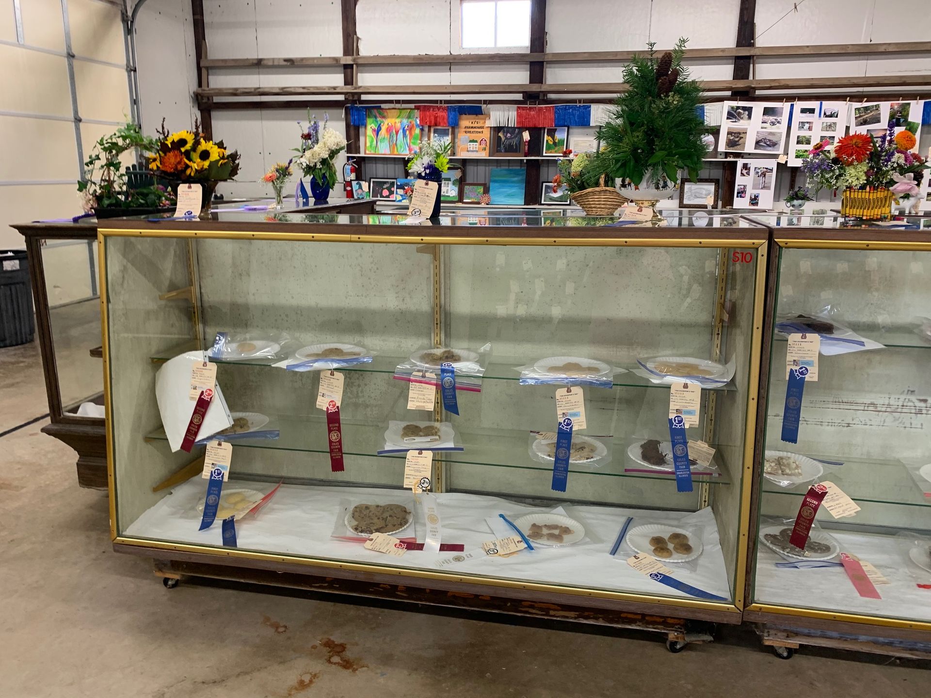 A glass display case filled with trophies and flowers.