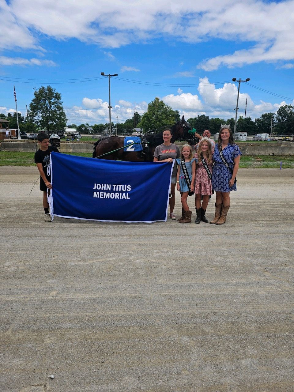 A group of people holding a blue banner that says john tetes international