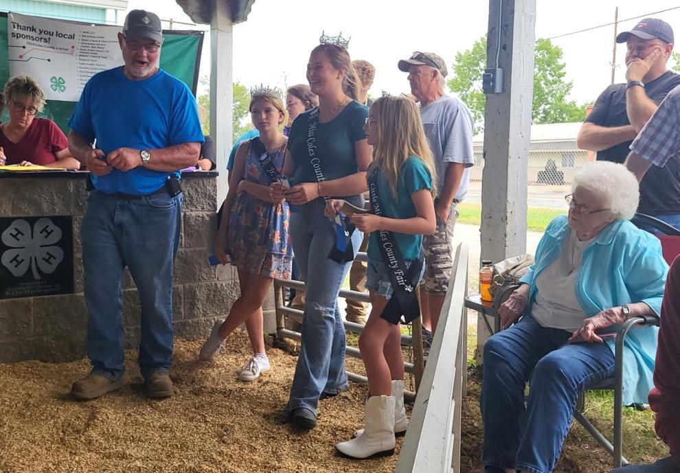 A group of people are standing around a fence at a fair.