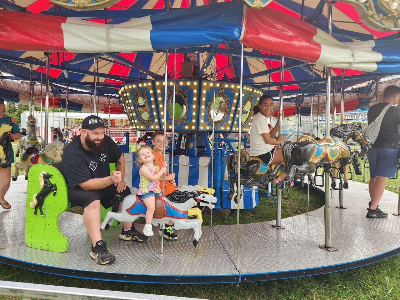 A man and two children are riding a merry go round.