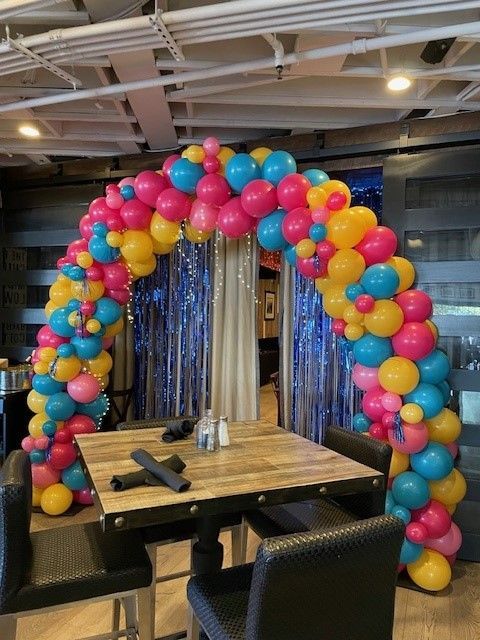 A restaurant with a table and chairs and a balloon arch