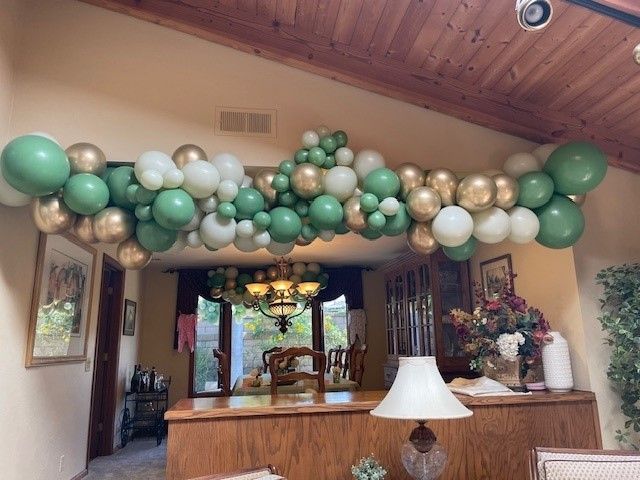 A living room with green and gold balloons hanging from the ceiling.