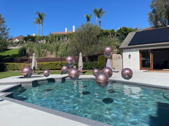 A bunch of balloons are floating in a pool