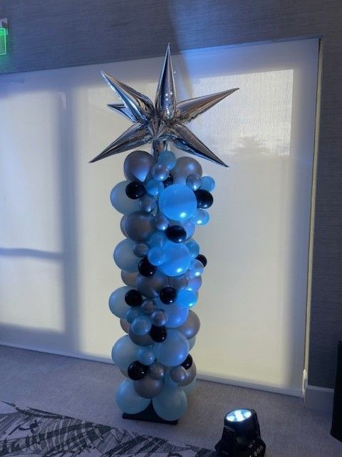 A pillar made of blue and silver balloons with a star on top