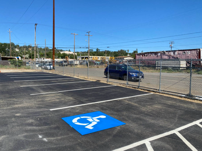 Empty parking lot with a blue accessible parking space marking and chain-link fence in the background