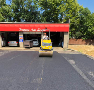 Yellow skid steer in front of Westside Auto Service garage with cars inside