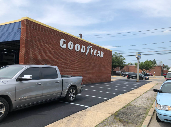 Goodyear tire store exterior with parked pickup truck and cars under a blue sky