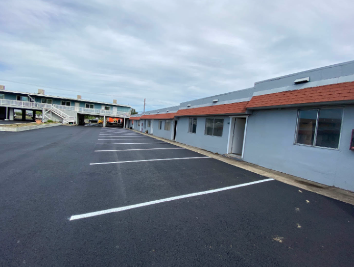 Empty parking lot beside a low motel building under a cloudy sky