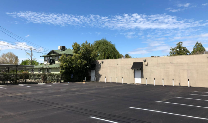 Empty parking lot beside a beige building under a blue sky.