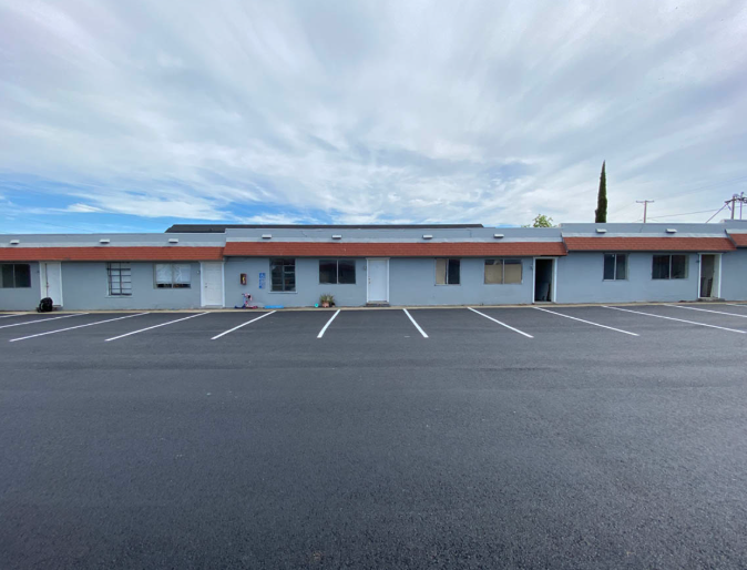 Single-story motel with empty parking lot under a cloudy sky