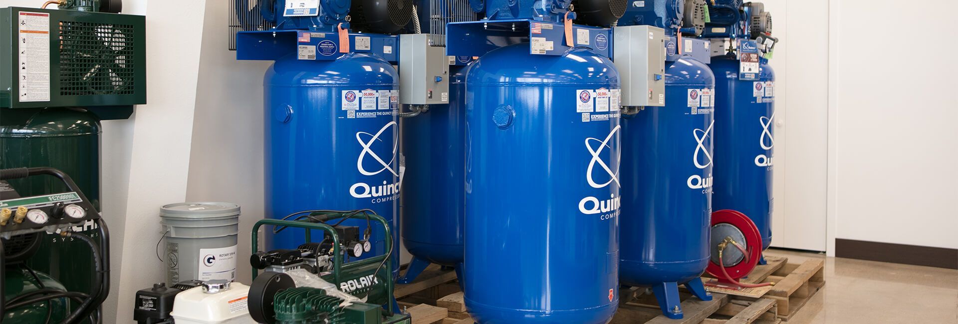 Blue industrial tanks and pumps in a utility room with pipes and equipment.