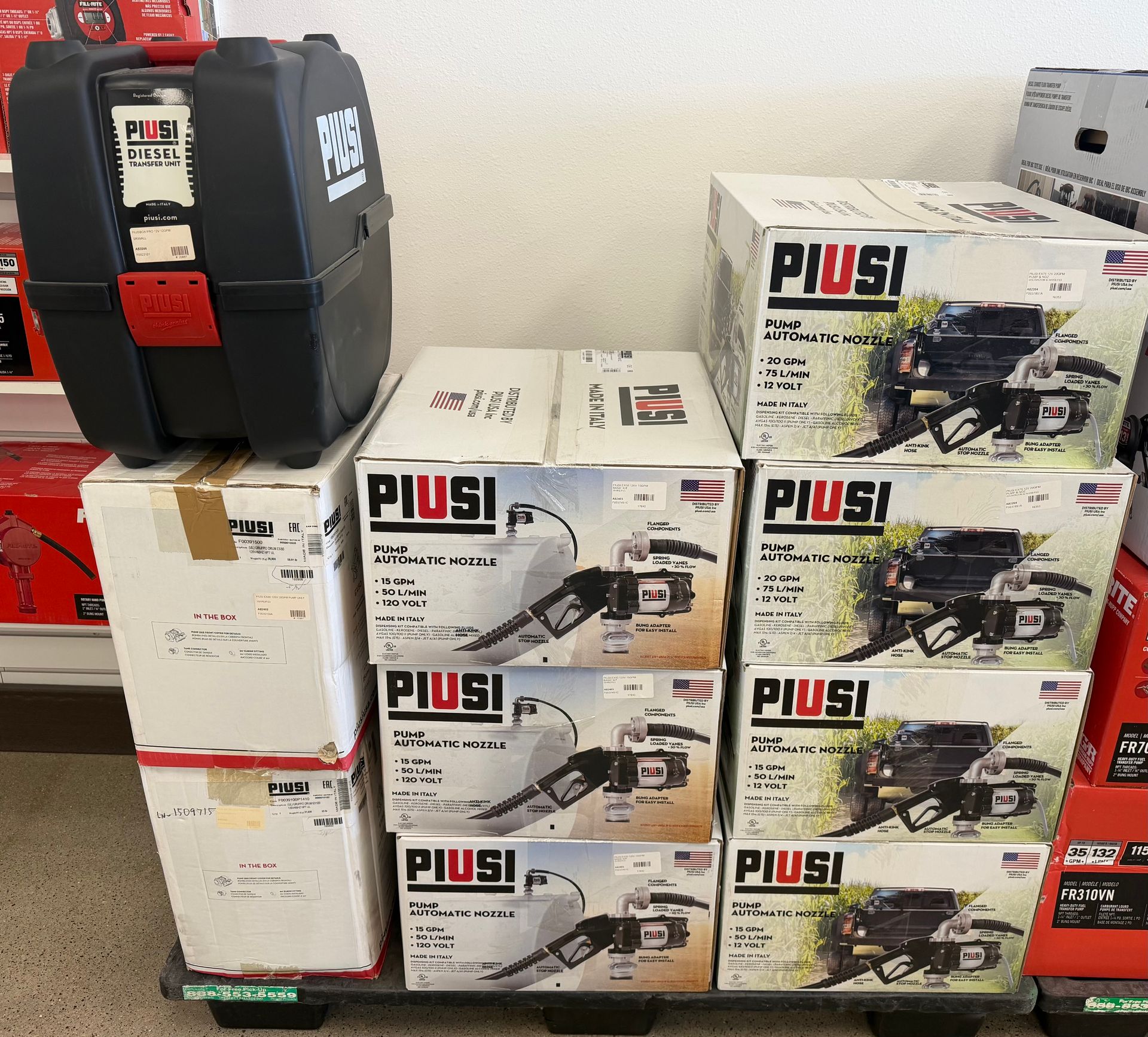 Stacked boxes of PIUSI equipment and a black fuel pump unit in a store aisle.
