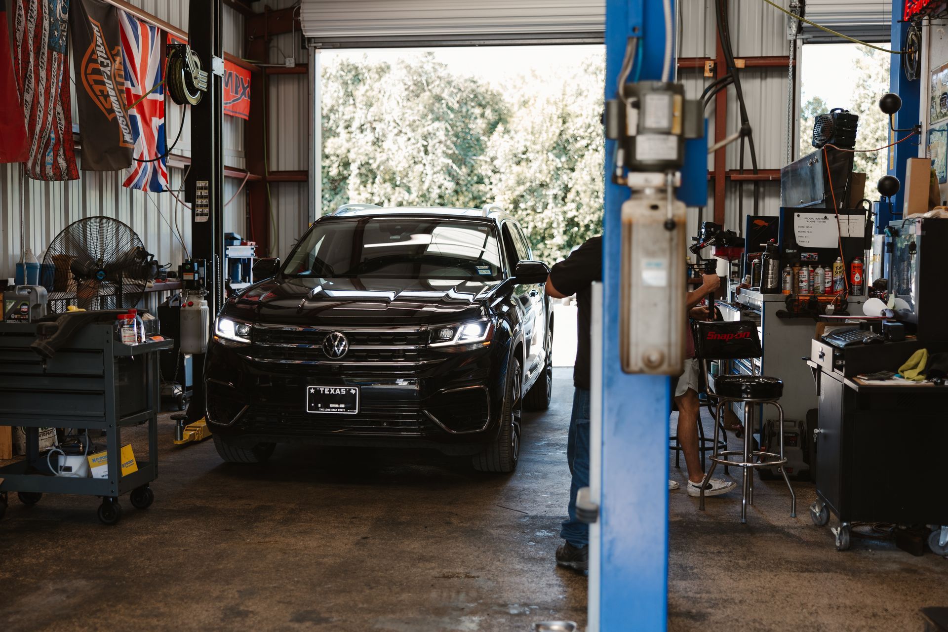 A man is working on a car underneath it in a garage.