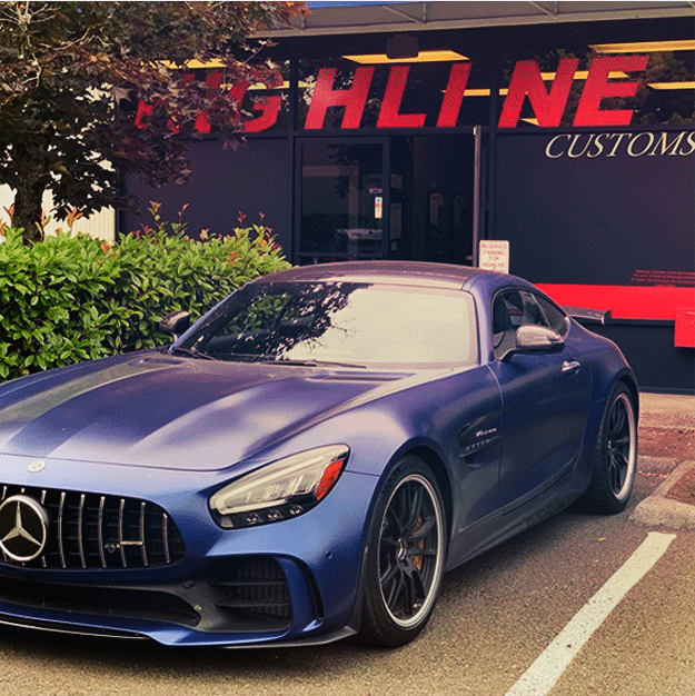 A blue car is parked in front of a building that says highline customs