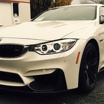 A white bmw m4 is parked in front of a house.