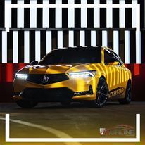 A yellow acura integra concept car is parked in front of a black and white striped wall.