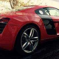A red audi r8 is parked on the side of the road.