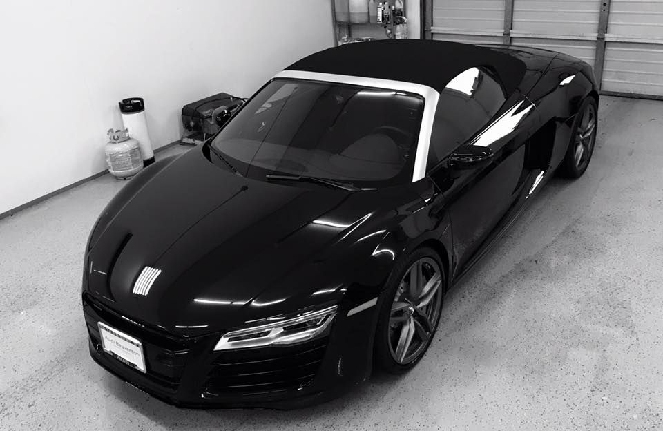 A black sports car is parked in a garage