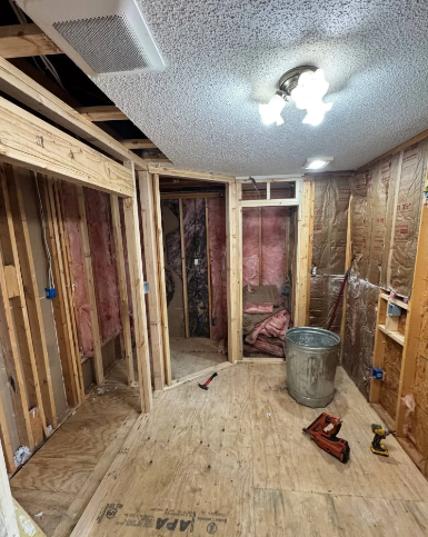 Unfinished room with exposed studs, insulation, bare subfloor, and a ceiling light under construction